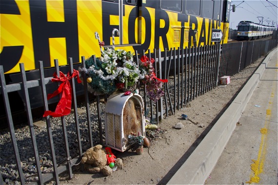 "Heads Up! Watch for Trains!" is seen on the train passing the memorial for Gilberto Reynaga, struck down by a Blue Line train at age 13 in 1999. Sahra Sulaiman/Streetsblog L.A.