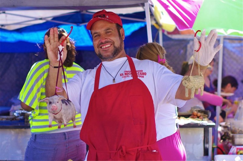 A street vendor in the piñata district holds up two cochinitos. Should the vending ordinance pass as currently structured, the presence of vendors in areas like the piñata district could be significantly curtailed. Sahra Sulaiman/Streetsblog L.A.